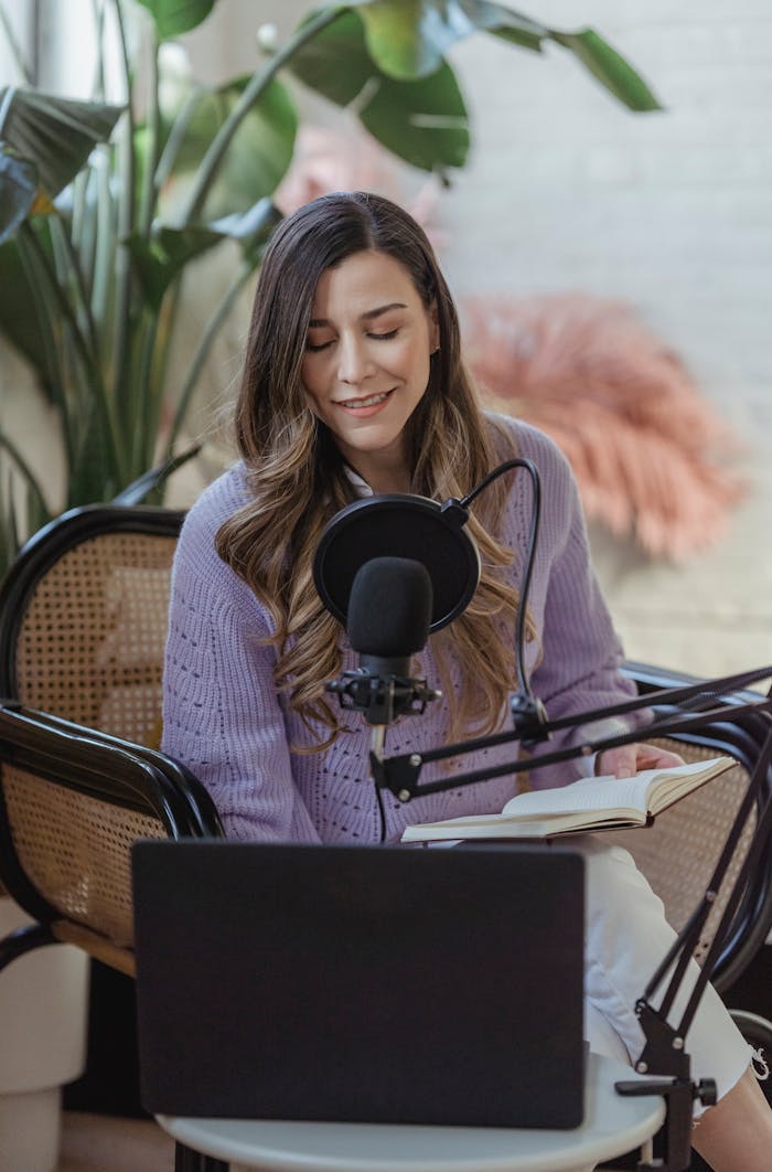 Smiling woman recording podcast on microphone with laptop